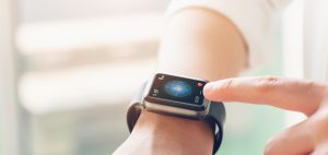 A hand is touching a smartwatch which is one of medical wearable devices