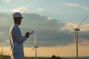 An engineer is checking wind turbine system with a tablet as an example of digitalizing wind energy