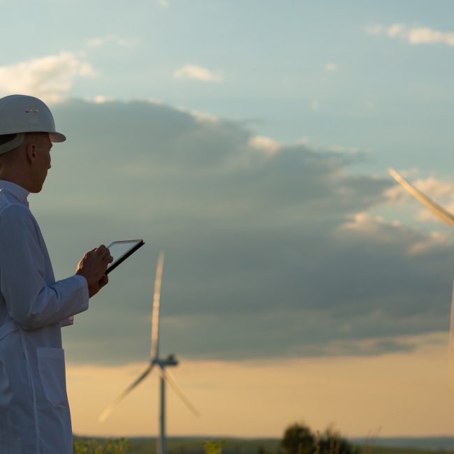An engineer is checking wind turbine system with a tablet as an example of digitalizing wind energy