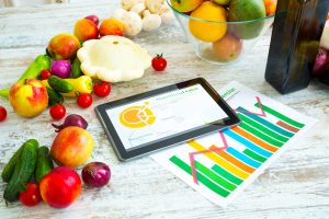 Organic food on the table and a tablet with a running diet applcation showing nutritional breakdown of ingredients