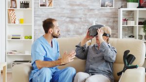 Male doctor in nursing home is helping a senior woman to use virtual reality goggles