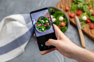 Shooting fresh vegetable salad with smartphone in order to get information on its nutrition data and keep up with healthy eating.