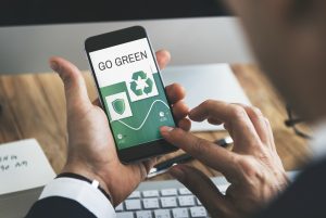 A man is holding a mobile phone displaying an application helping to protect environment like e.g. a carbon footprint calculator 